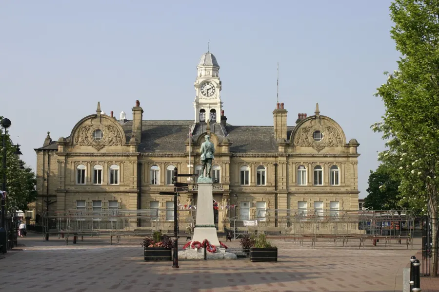 Ossett town hall on a clear day with memorial statue visible.
